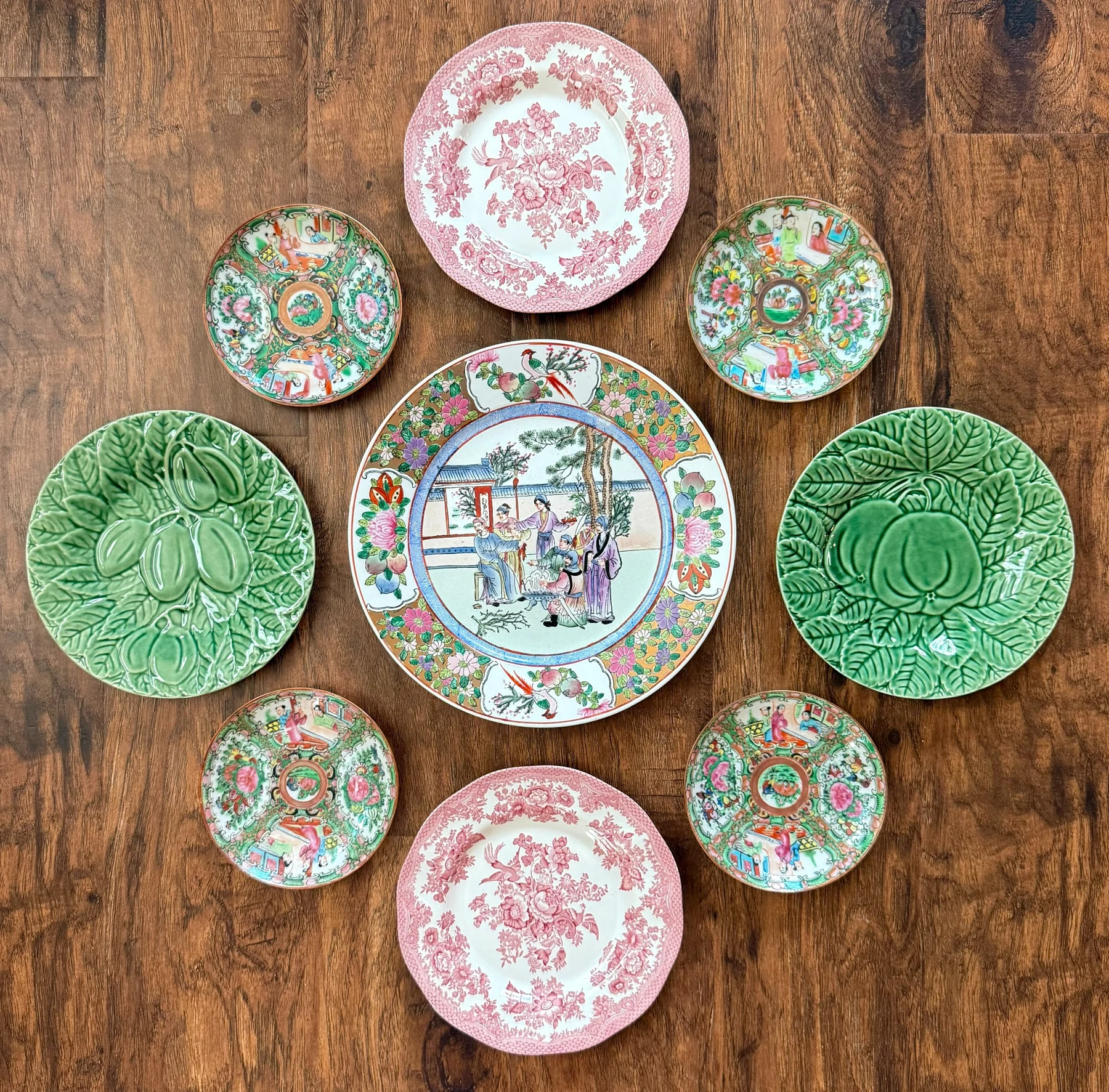 Green, rose medallion and pink transferware plate arrangement laid out on wood