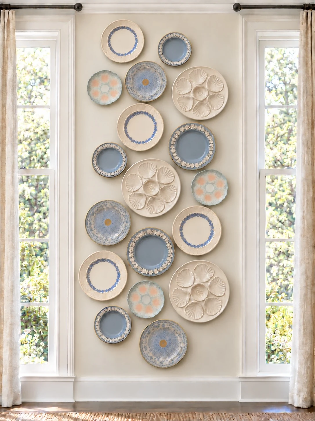 Soft blue and white plate wall arranged between two windows